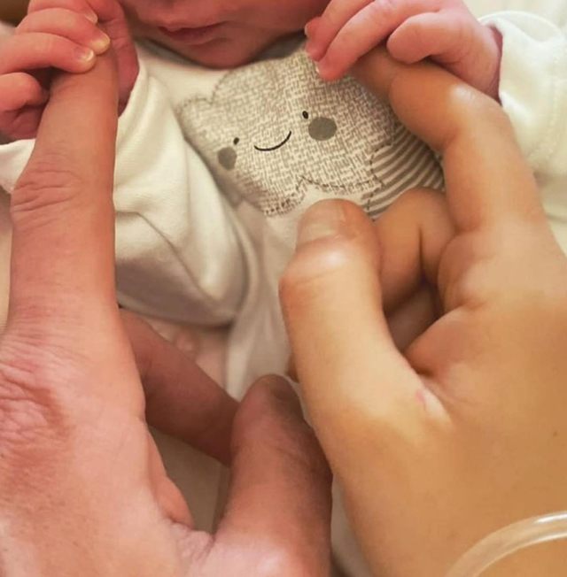 La piccola Ginevra, nata poco dopo la mezzanotte di martedì 27 aprile, stringe le dita dei genitori